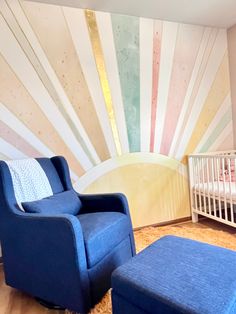 a baby's room with a blue chair and crib in the corner, next to a large wall mural