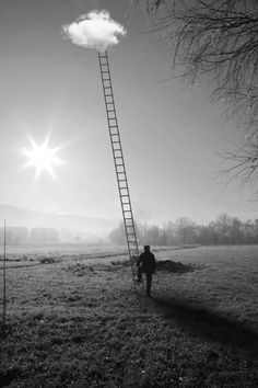 a man walking towards a ladder in the middle of a field