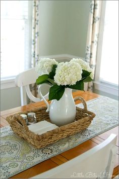 a white vase filled with flowers on top of a wooden table