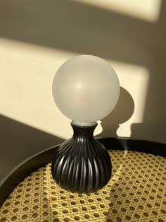 a white ball sitting on top of a table next to a shadow from a window