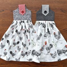 two dresses with chickens on them are sitting on a wooden table next to each other