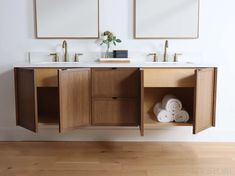 a bathroom with two sinks and mirrors on the wall next to each other in front of a wooden floor