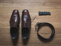 a pair of brown shoes sitting on top of a wooden floor next to a cord