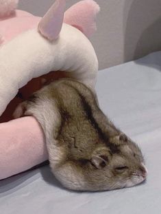 a stuffed animal laying on top of a bed next to a pink bunny rabbit pillow