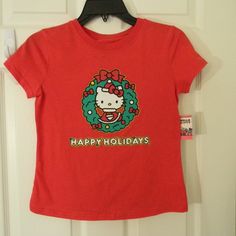 This Adorable Girls' Tee Features Everyone's Favorite Feline, Hello Kitty, Dressed In Her Festive Best For Christmas! The Shirt Is Brand New With Tags And Comes In A Vibrant Red Color That's Perfect For The Holiday Season. Made By Sanrio, The World-Renowned Creator Of Hello Kitty, This Shirt Is Sure To Delight Fans Of All Ages. The Short-Sleeved T-Shirt Is A Size 12 And Features A Cute And Colorful Design That Showcases Hello Kitty Surrounded By Snowflakes And Other Holiday-Themed Imagery. It's Red Short Sleeve Holiday Top, Red Short Sleeve Top For Holidays, Cute Cotton Holiday Tops, Cute Red Holiday Tops, Cute Red T-shirt For Winter, Cute Red Winter T-shirt, Festive Red Short Sleeve Tops, Red Hello Kitty Short Sleeve Tops, Cute Holiday Graphic Print Tops