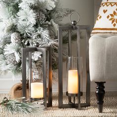 two lit candles sitting on top of a rug next to a christmas tree with pine cones