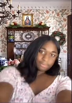 a woman taking a selfie in front of a christmas tree and wallpapered walls