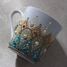 a white coffee cup with blue and gold designs on the side, sitting on a table