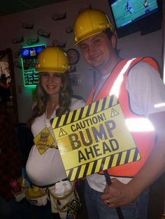 a man and woman in hard hats pose for a photo while holding a sign that says caution bump ahead