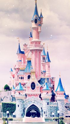 the castle is pink and has blue turrets on it's sides, with snow falling from the sky in the background