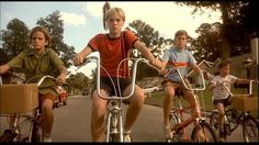 three children riding bikes down the street in front of their parents and dads on bicycles