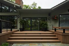 an outdoor patio with wooden steps and planters on each side, surrounded by large windows