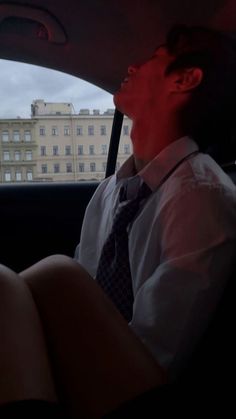 a man sitting in the back seat of a car wearing a tie and dress shirt