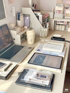 a laptop computer sitting on top of a desk next to a desktop computer and other office supplies