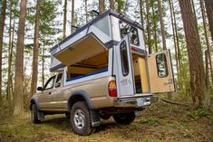 a truck with a camper attached to it's bed parked in the woods