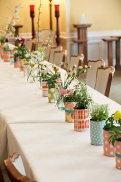 a long table with many vases filled with flowers and plants on top of it