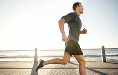 a man is running on the boardwalk near the water and beach in front of him