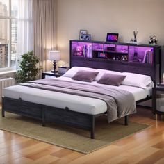 a bedroom with a bed, nightstands and window in the background is lit by purple lights