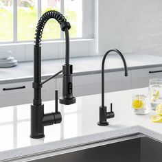 a kitchen sink with a faucet and two glasses on the counter next to it