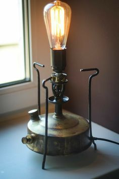 an old fashioned lamp sitting on top of a table next to a window with the light turned on