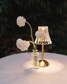 Elegant wedding table detail with white ranunculus in crystal bud vase next to gold vintage-style table lamp Paper Lanterns Outdoor Wedding, Table Lamp Centerpieces Wedding Reception, Lamps At Wedding, Lamp Wedding Centerpiece, Table Lamp Wedding, Wedding Table Lamps, Lamp Centerpiece Wedding, Diy Wedding Table Centerpieces, Lamp Wedding Decor