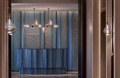 the interior of a modern hotel lobby with chandelier and blue curtained walls