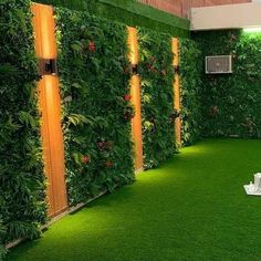 an indoor living room with artificial grass and plants on the walls, along with lights