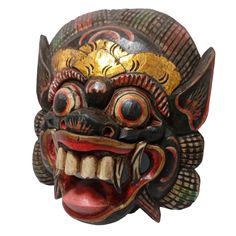 a wooden mask with red and yellow paint on it's face, showing the teeth