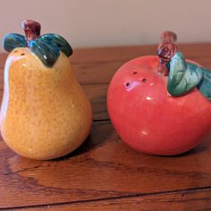 two ceramic fruits sitting on top of a wooden table