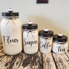 four jars with the words flour sugar and tea on them