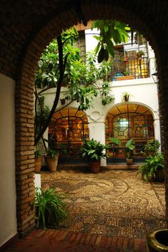 an archway leading into a courtyard with potted plants