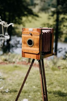 an old fashioned wooden camera sitting on top of a tripod in front of some trees