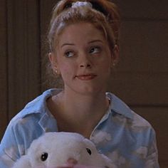 a woman holding a white stuffed animal in her arms and looking up at the camera