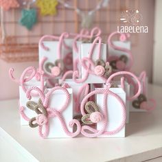 small white boxes with pink ribbons and bows on them sitting on a table in front of a wall