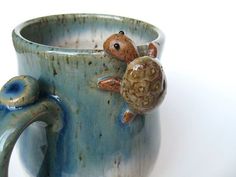 a ceramic mug with a turtle on the inside and a shell on the outside, sitting in front of a white background