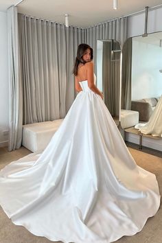 a woman in a white wedding dress looking at herself in the mirror