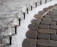 there are many lights that are on the brick path in the snow, and it looks like they have been blown off