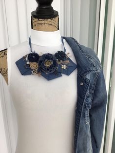 a white top with a denim jacket and blue flowers on the collar, next to a mannequin