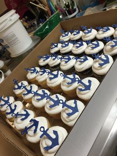 cupcakes decorated with blue and white frosting are in a box on a table