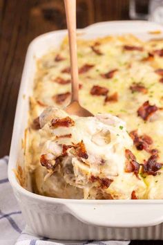 a casserole dish with chicken and bacon in it being lifted by a wooden spoon