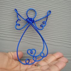 a hand holding a blue wire angel ornament