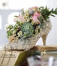 a pair of shoes sitting on top of a table next to a book with flowers in it