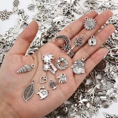 a person's hand is full of silver charms