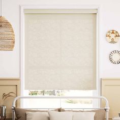 a living room with a couch and window covered in white roman blind shades on the windowsill