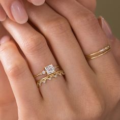 a woman's hand with two gold rings on it and a diamond ring in the middle