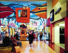 people are walking through an indoor mall with brightly colored decorations on the walls and ceiling