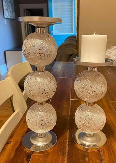 three glass balls sitting on top of a wooden table next to a white candle holder