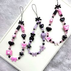 two necklaces with black, pink and purple beads are on top of a white surface