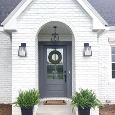 a gray front door with two black planters