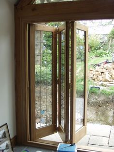 an open wooden door sitting next to a window on top of a stone flooring area